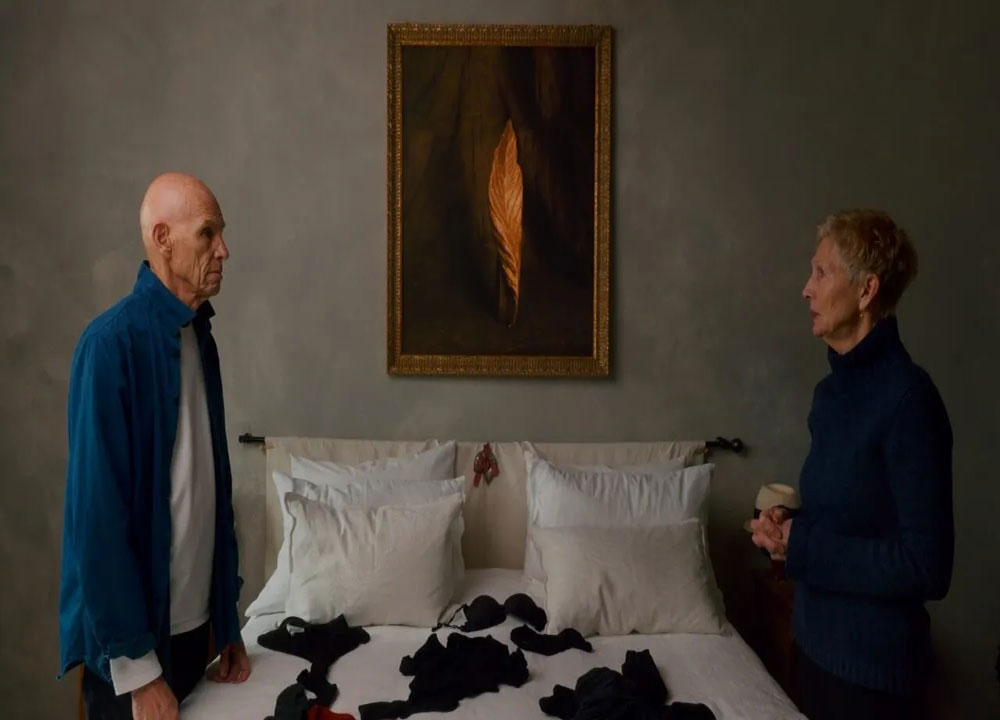 Joel Meyerowitz and Maggie Barrett stare at each other from across the room.